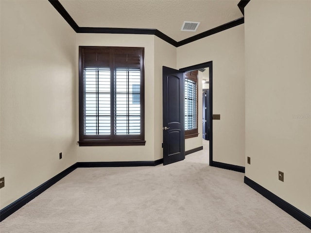 unfurnished room featuring visible vents, light carpet, baseboards, and crown molding