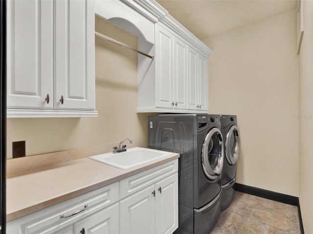 clothes washing area featuring cabinet space, washer and dryer, baseboards, and a sink