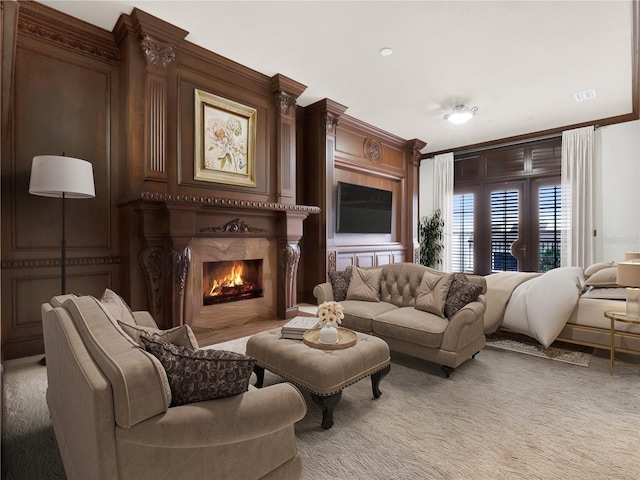 carpeted living room with crown molding, visible vents, and a premium fireplace