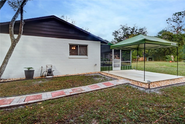 exterior space featuring a gazebo, a sunroom, a patio area, and a lawn