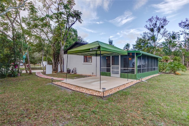 rear view of property with a lawn, a sunroom, and a patio