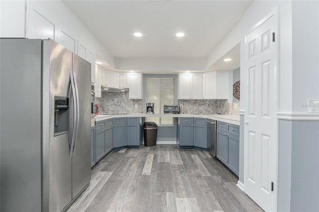 kitchen with backsplash, light hardwood / wood-style flooring, white cabinets, and stainless steel appliances