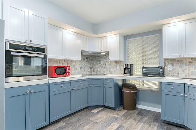 kitchen with decorative backsplash, black electric stovetop, dark hardwood / wood-style flooring, stainless steel oven, and white cabinets