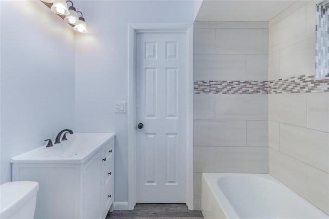 bathroom featuring hardwood / wood-style floors, vanity, toilet, and a bathing tub