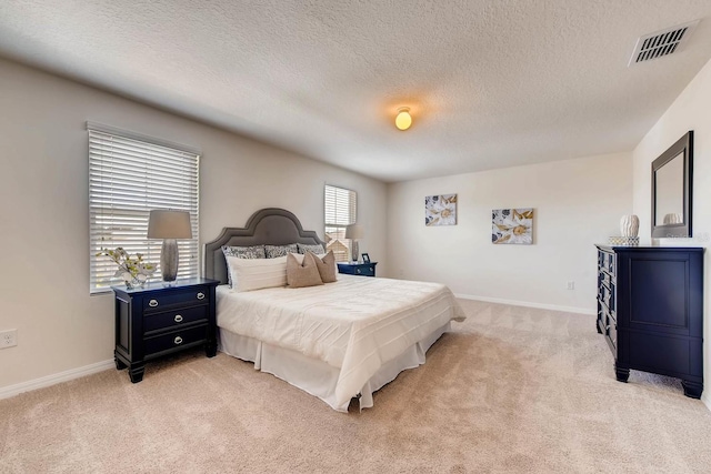 bedroom with multiple windows, a textured ceiling, and light carpet