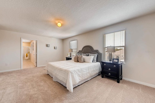 carpeted bedroom with ensuite bathroom and a textured ceiling