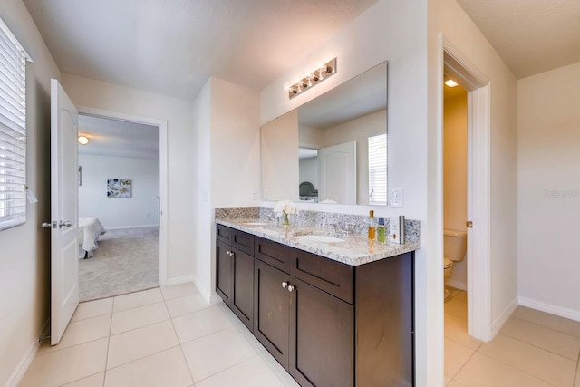 bathroom featuring toilet, vanity, tile patterned floors, and a healthy amount of sunlight