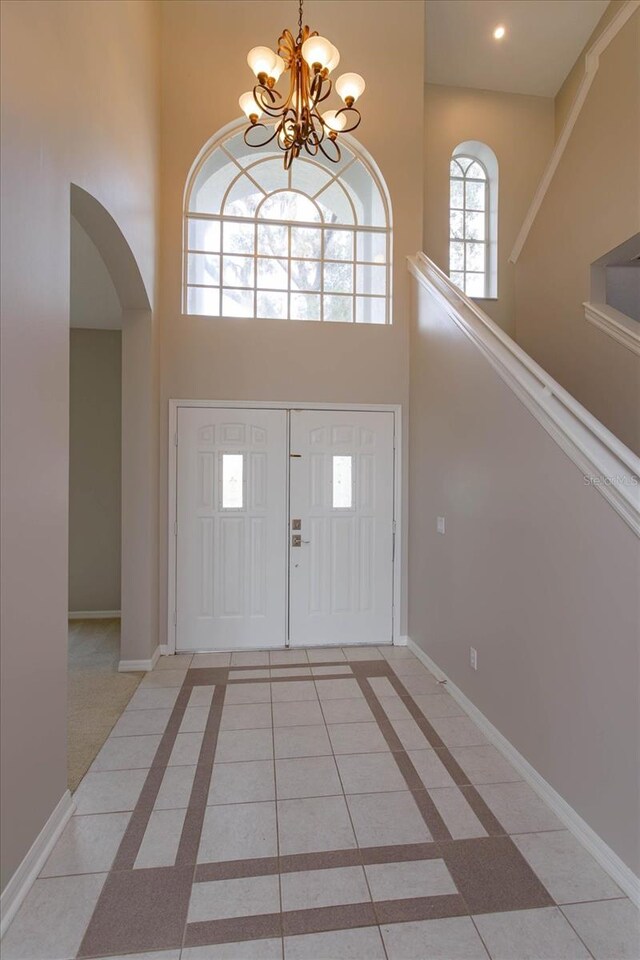 foyer with light tile patterned floors, a high ceiling, and an inviting chandelier