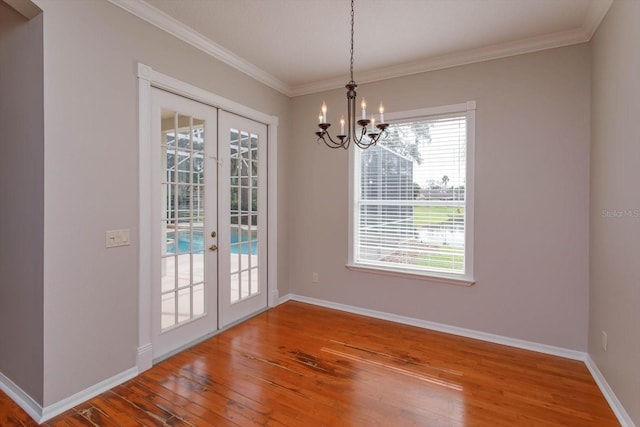 unfurnished dining area featuring a wealth of natural light, wood-type flooring, french doors, and ornamental molding