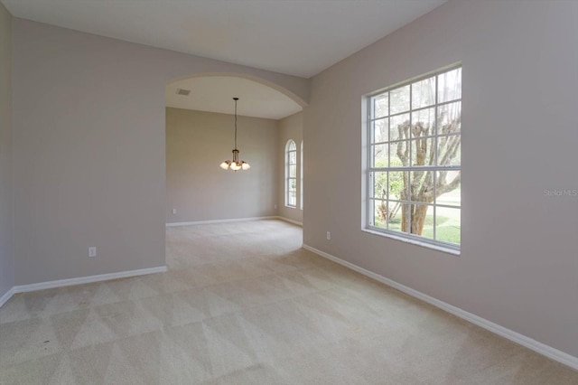 carpeted empty room with an inviting chandelier