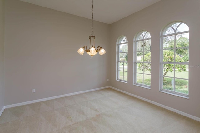 carpeted empty room with plenty of natural light and a notable chandelier