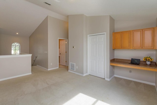 kitchen with built in desk, light colored carpet, and vaulted ceiling