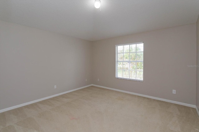 spare room featuring light colored carpet and a textured ceiling