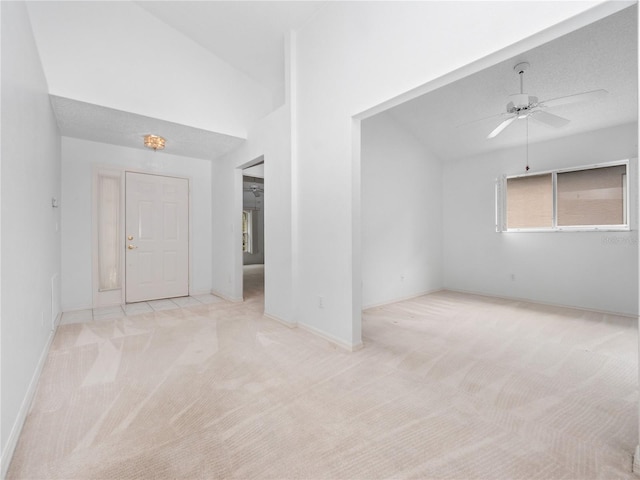 empty room featuring light carpet, ceiling fan, and vaulted ceiling