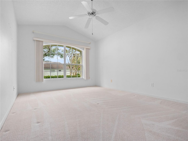 spare room featuring lofted ceiling, a textured ceiling, light colored carpet, and ceiling fan