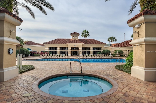 view of swimming pool featuring a hot tub and a patio