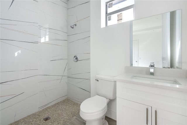 bathroom featuring vanity, toilet, and a tile shower