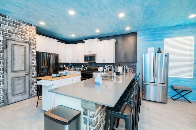 kitchen featuring a breakfast bar, white cabinets, stainless steel appliances, and sink