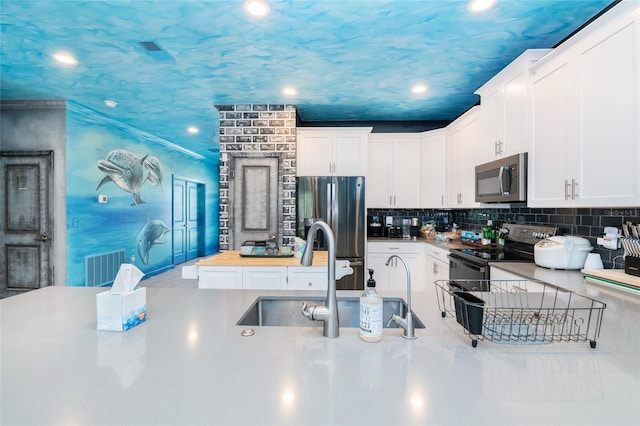 kitchen featuring tasteful backsplash, stainless steel appliances, sink, white cabinets, and butcher block countertops