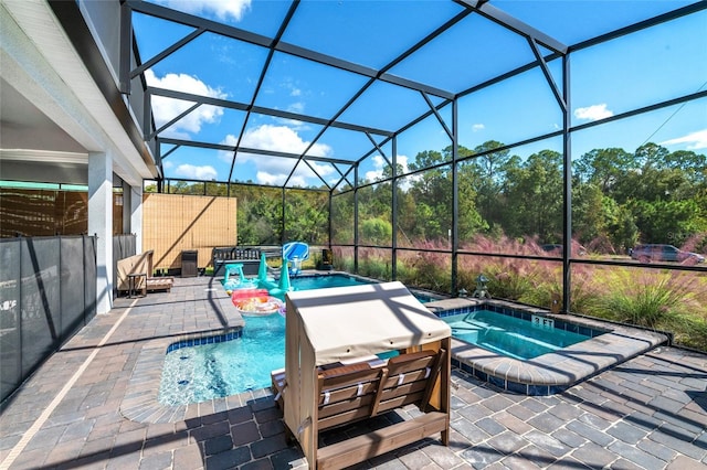 view of pool featuring an in ground hot tub, glass enclosure, and a patio area