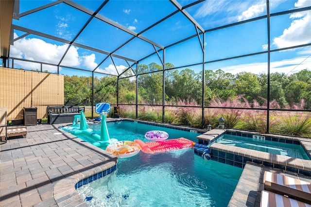 view of swimming pool with glass enclosure, an in ground hot tub, and a patio area