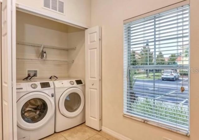 laundry area with washing machine and clothes dryer and light tile patterned floors