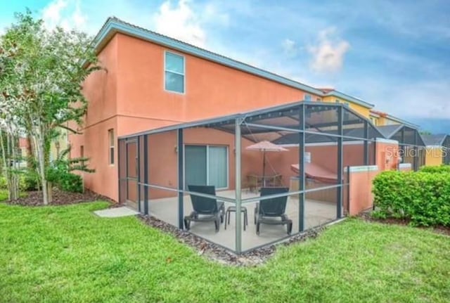 rear view of house with a lanai, a patio, and a yard