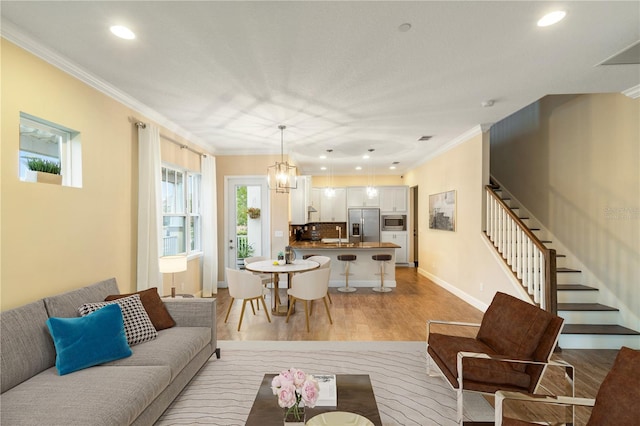 living room featuring light hardwood / wood-style floors, ornamental molding, and a notable chandelier