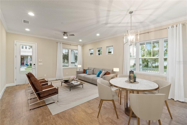 dining room featuring crown molding, light hardwood / wood-style flooring, and ceiling fan with notable chandelier