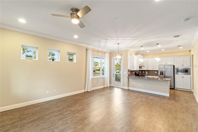 kitchen featuring white cabinetry, stainless steel appliances, kitchen peninsula, pendant lighting, and ceiling fan with notable chandelier