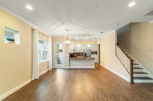 unfurnished living room featuring dark hardwood / wood-style flooring, a notable chandelier, and ornamental molding