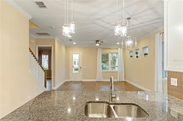 kitchen featuring ceiling fan with notable chandelier, crown molding, sink, wood-type flooring, and stone countertops