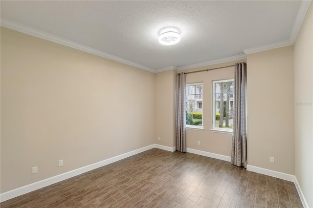 spare room featuring a textured ceiling, wood finished floors, baseboards, and ornamental molding