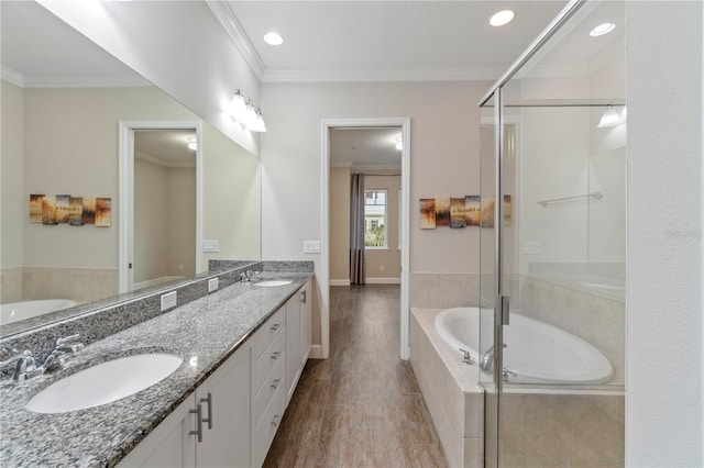 bathroom featuring a sink, double vanity, a bath, and crown molding