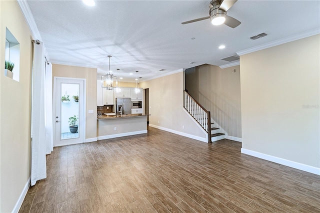 unfurnished living room featuring visible vents, ornamental molding, stairs, baseboards, and dark wood-style flooring