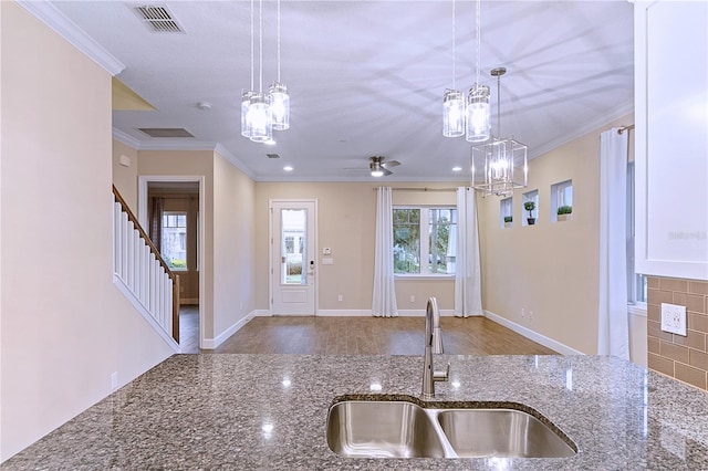 kitchen with a sink, visible vents, ornamental molding, and decorative light fixtures