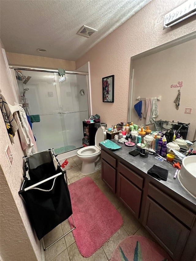 bathroom with tile patterned flooring, a textured ceiling, vanity, an enclosed shower, and toilet