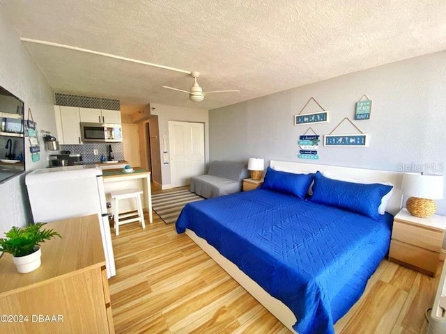 bedroom featuring light hardwood / wood-style floors, a textured ceiling, and ceiling fan