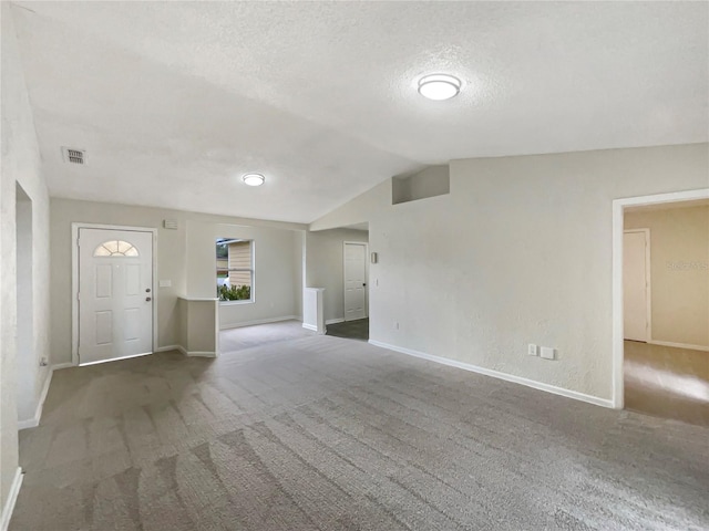 unfurnished living room with lofted ceiling, a textured ceiling, and dark carpet