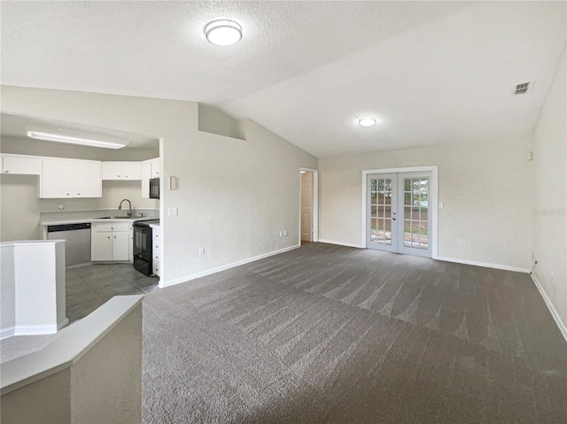 unfurnished living room featuring french doors, lofted ceiling, sink, and dark carpet