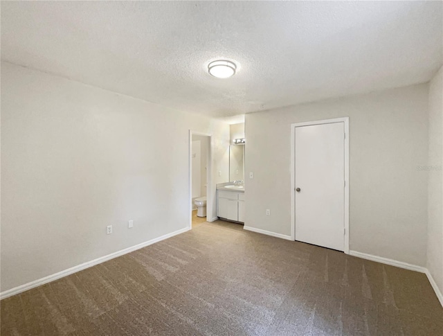 carpeted spare room featuring sink and a textured ceiling