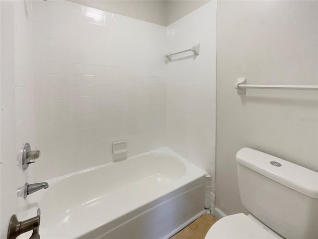 bathroom featuring tile patterned floors, tiled shower / bath, and toilet