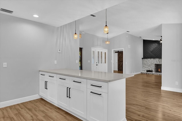 kitchen featuring hardwood / wood-style floors, ceiling fan, a premium fireplace, decorative light fixtures, and white cabinetry