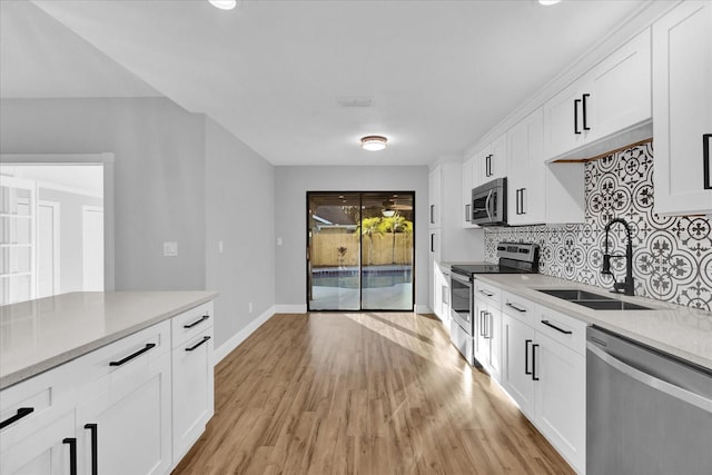 kitchen with white cabinets, backsplash, sink, and stainless steel appliances