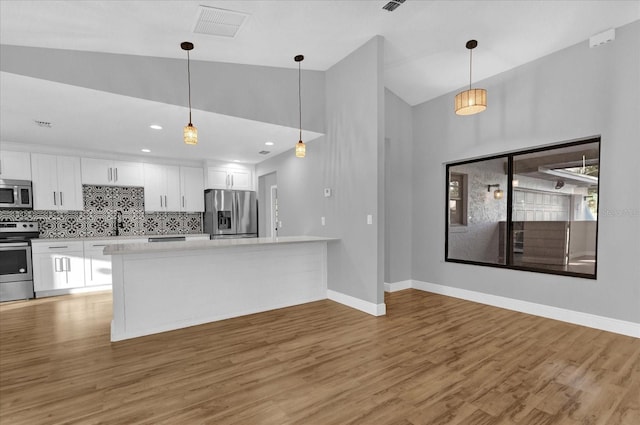 kitchen with backsplash, white cabinetry, stainless steel appliances, and light hardwood / wood-style floors