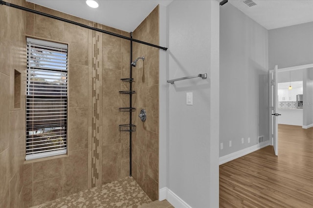 bathroom with hardwood / wood-style floors and a tile shower