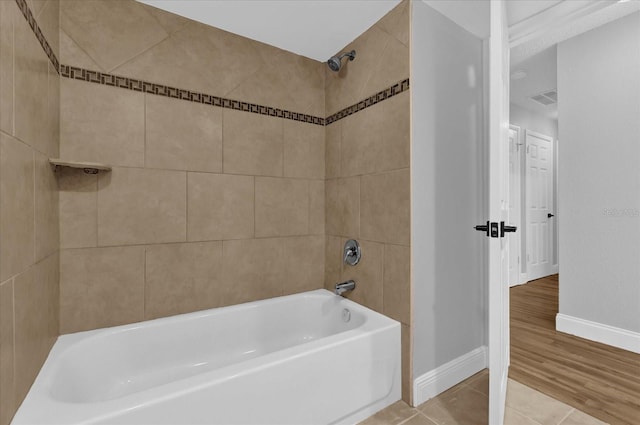 bathroom with hardwood / wood-style floors and tiled shower / bath combo