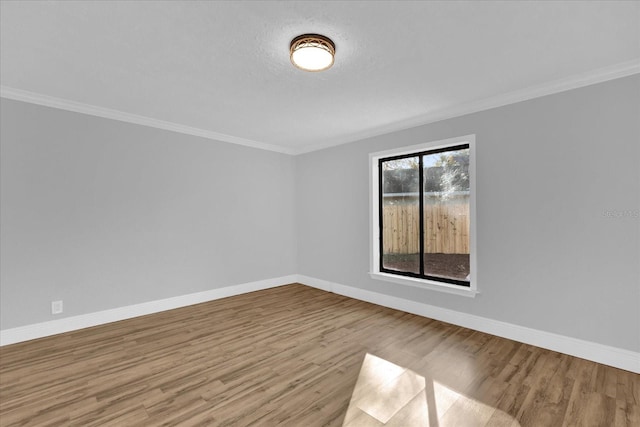 empty room with crown molding and light hardwood / wood-style flooring