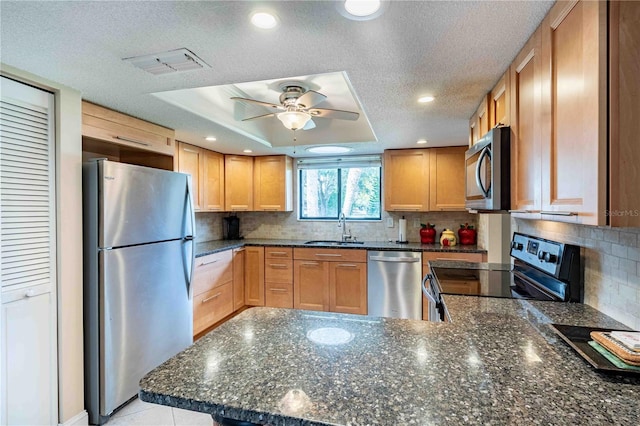 kitchen with appliances with stainless steel finishes, backsplash, a textured ceiling, a raised ceiling, and sink