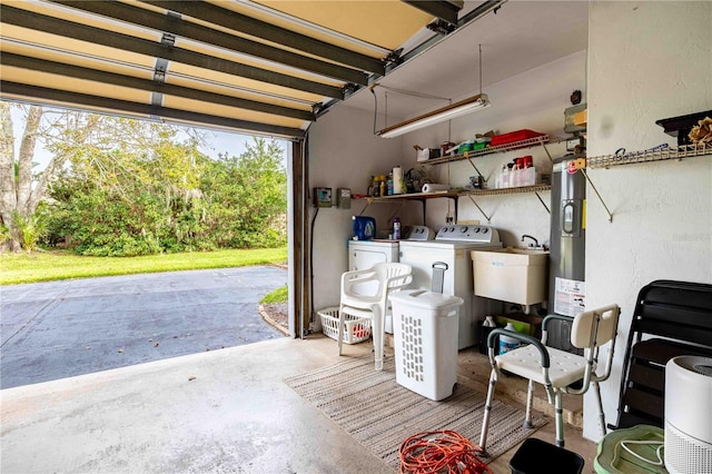 garage with washing machine and clothes dryer, water heater, and sink